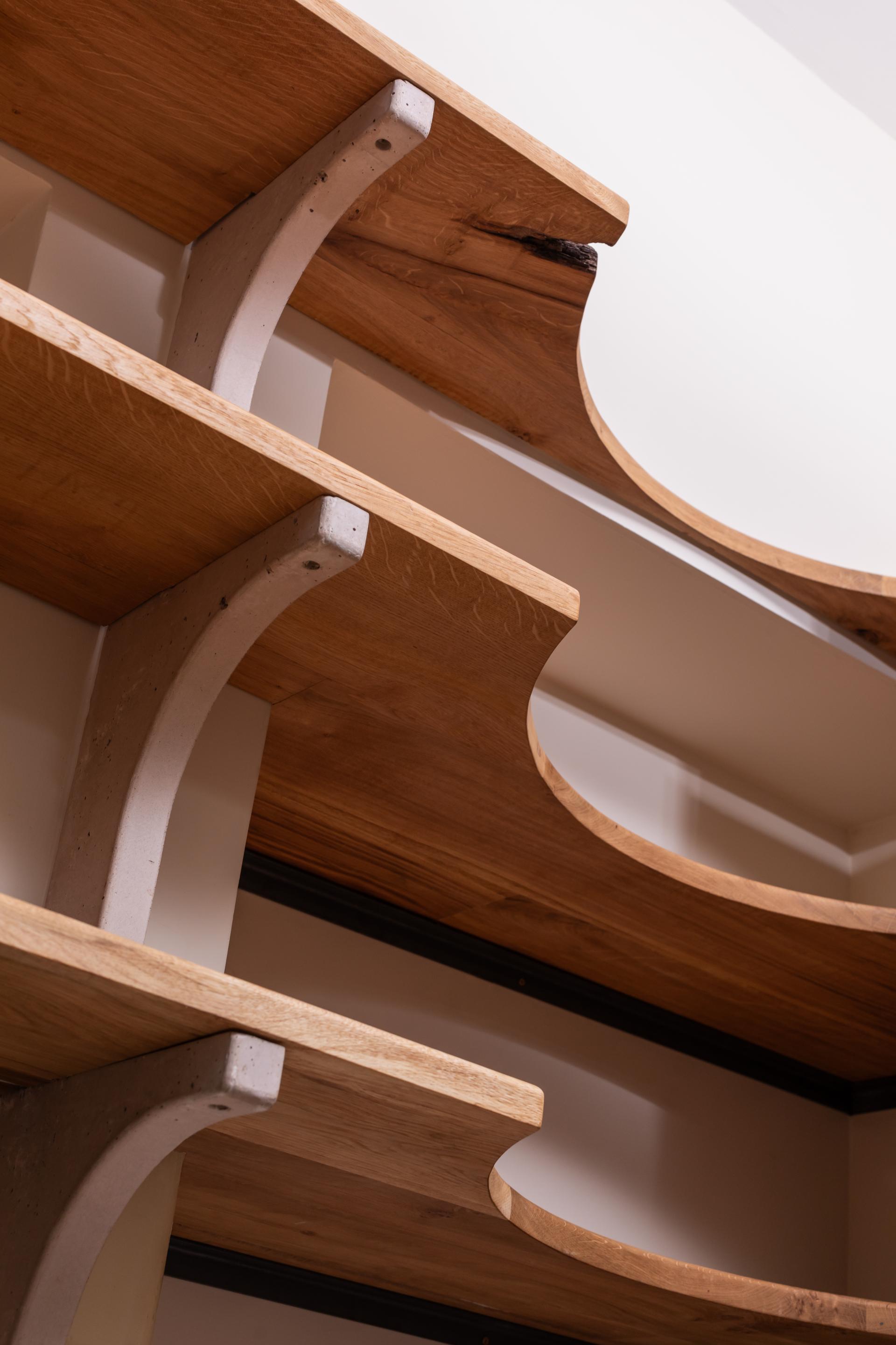Curved Scottish Oak shelves with concrete supports, showcasing elegant design in a contemporary kitchen setting.
