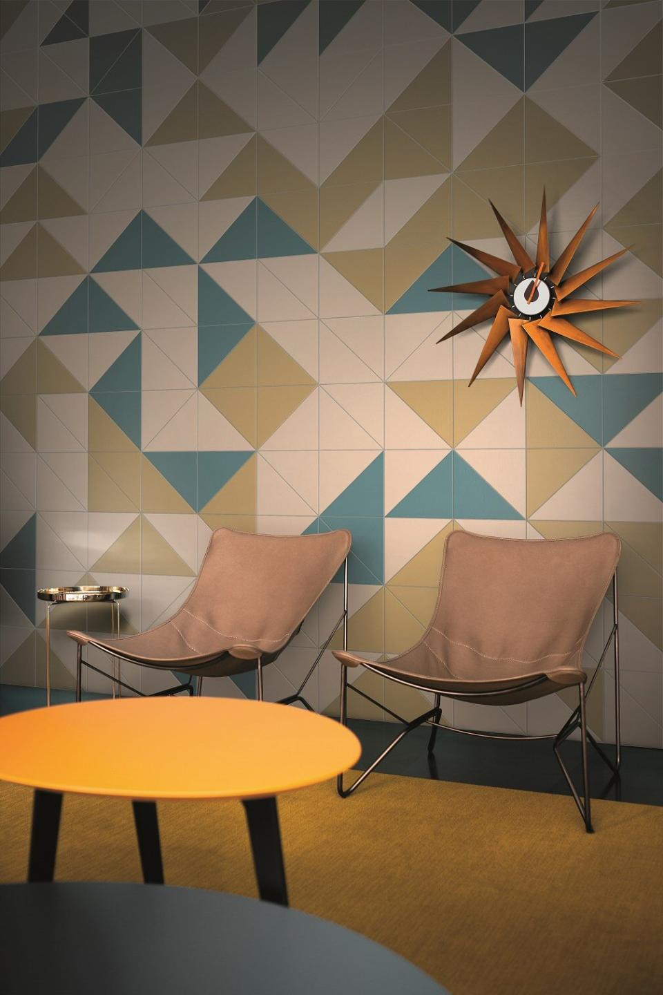Colorful porcelain tile wall design from the Pittorica collection, featuring stylish chairs and modern decor elements.