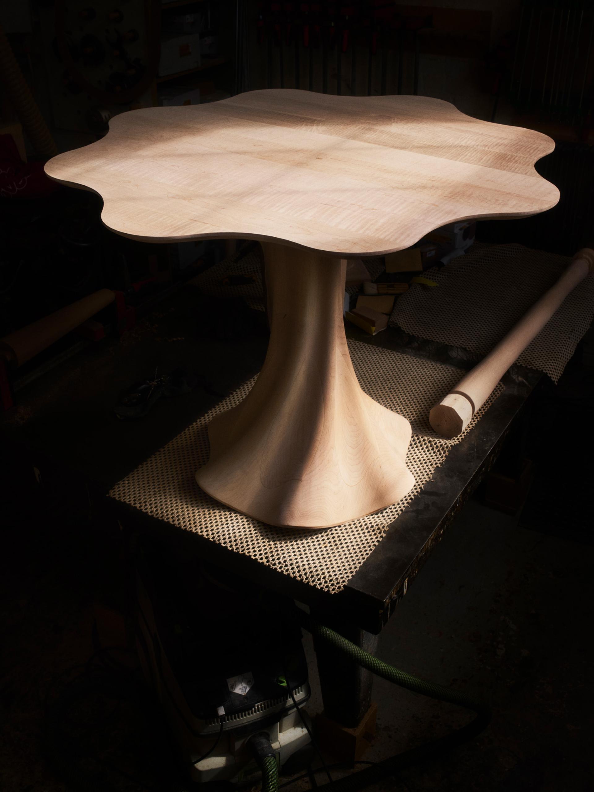 Sculptural wooden table with an organic shape, crafted by Jan Hendzel, highlighting traditional and modern woodworking techniques.