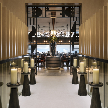 Elegant Art Deco hallway leading to a sophisticated dining area adorned with candles and modern decor at The Upper House, Hong Kong.