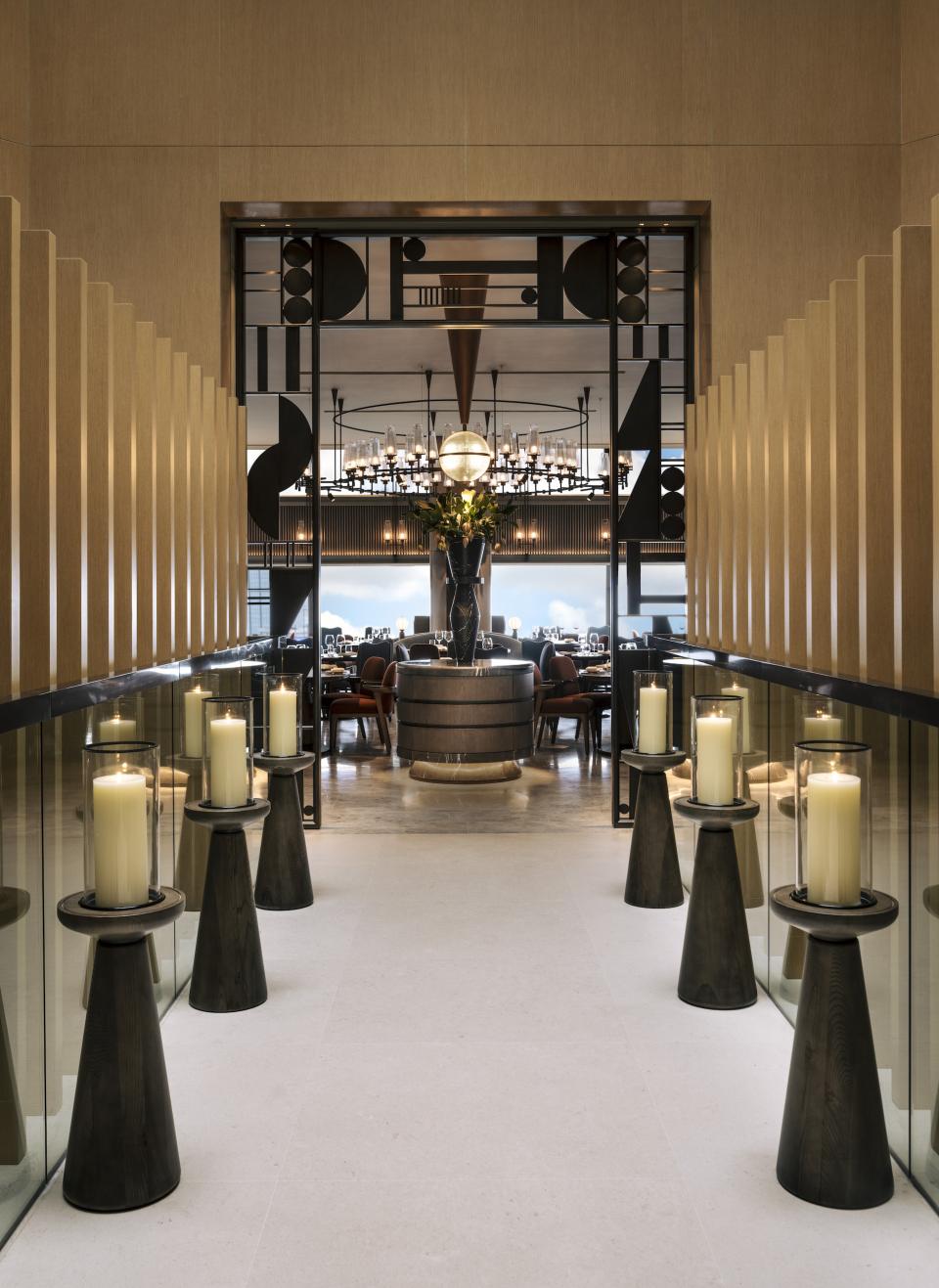 Elegant Art Deco hallway leading to a sophisticated dining area adorned with candles and modern decor at The Upper House, Hong Kong.