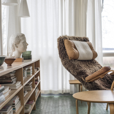Interior view of Karin and Bruno Mathsson's home, featuring a stylish rocking chair, wooden bookshelf, and modern decor.