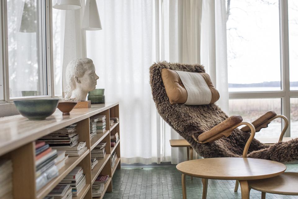 Interior view of Karin and Bruno Mathsson's home, featuring a stylish rocking chair, wooden bookshelf, and modern decor.