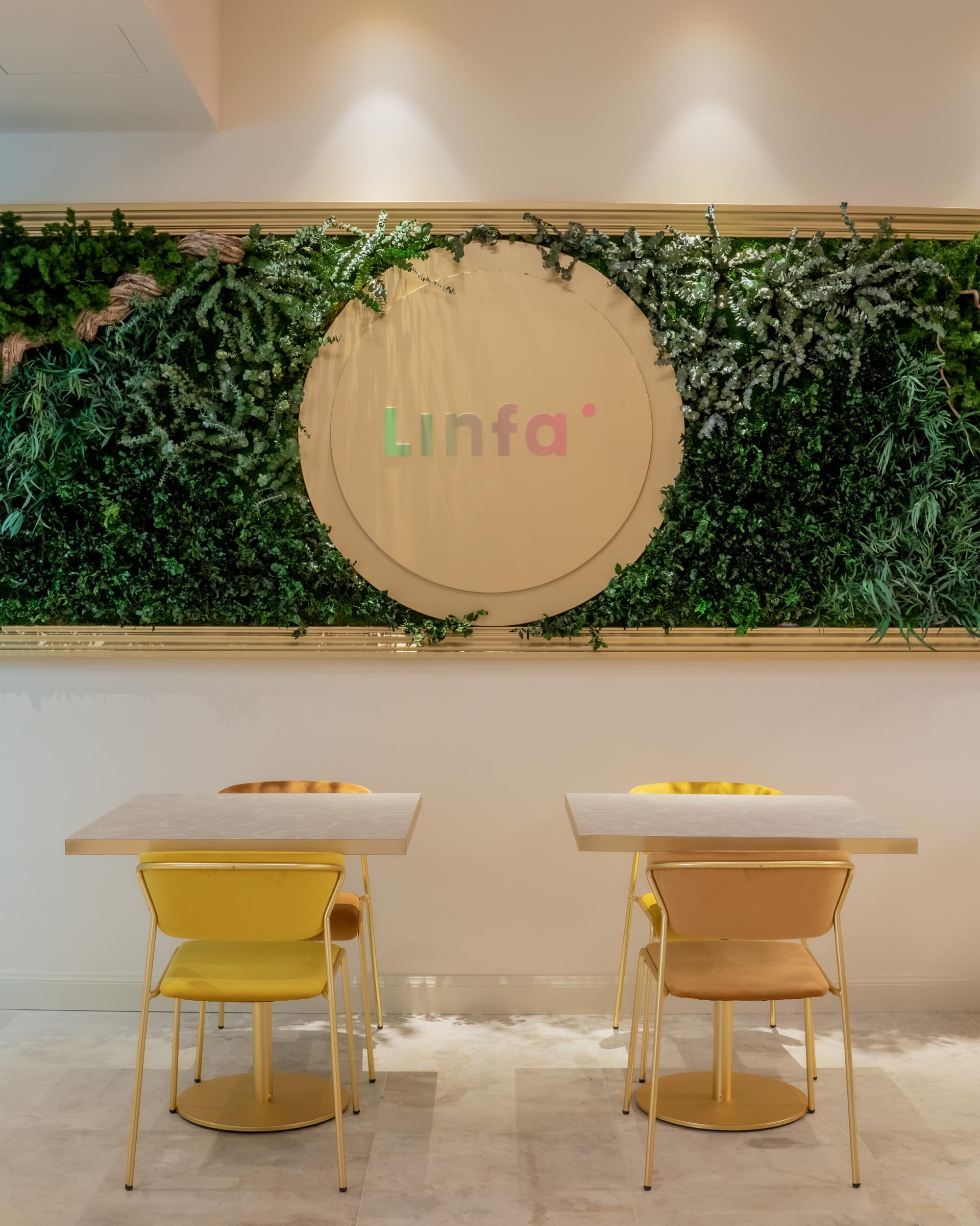 Modern dining area at Linfa Milano featuring yellow S•CAB chairs and lush greenery backdrop.