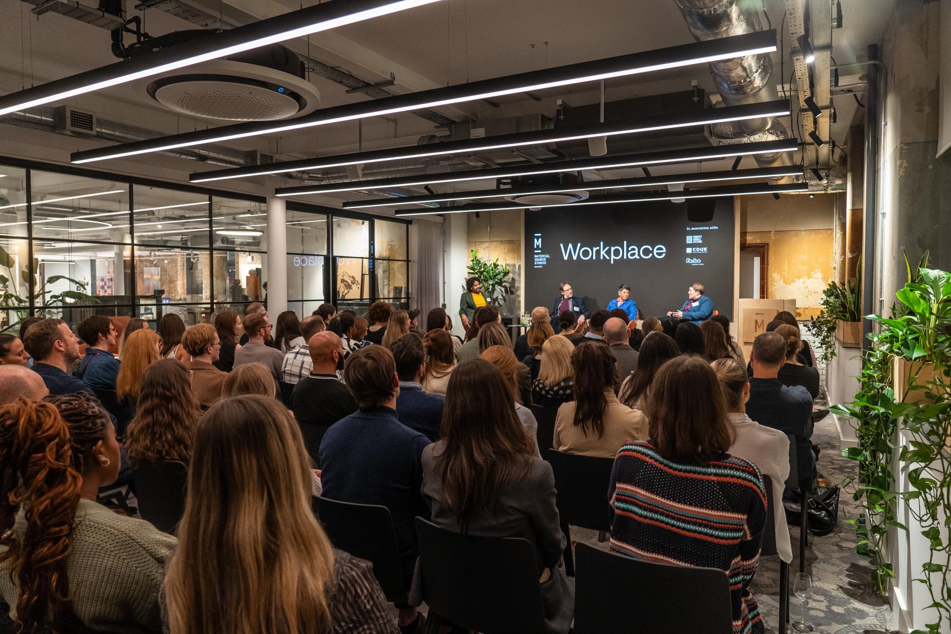 Panel discussion on modern workplace trends, featuring speakers and an audience in a stylish, contemporary setting.