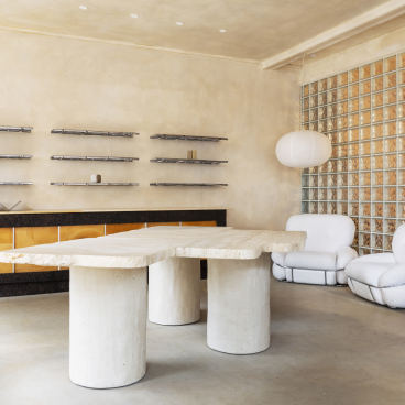 Stylish interior of big. store features salvaged materials, sculpture-like table, and modern, sustainable furniture design.