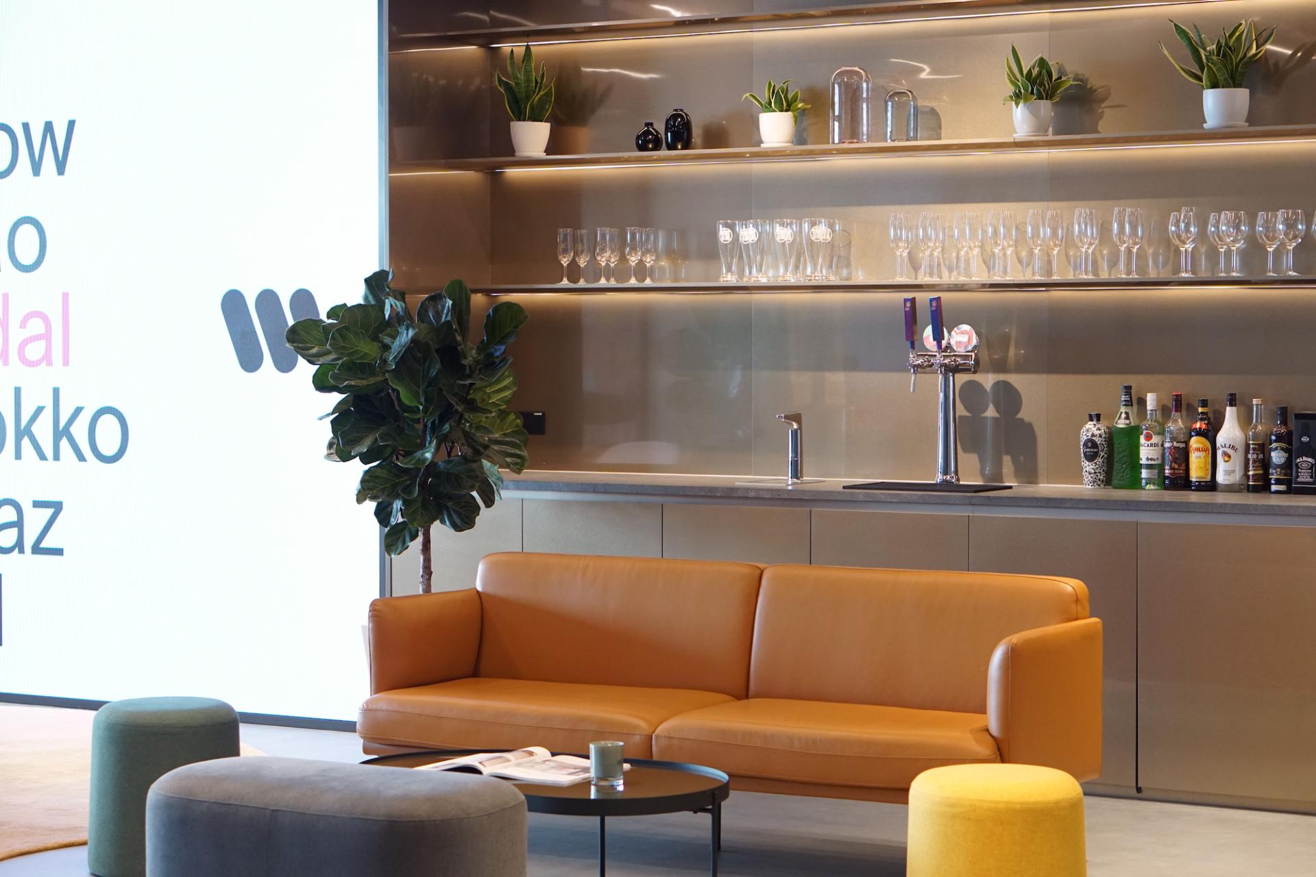 Stylish reception area of Warner Music Hong Kong, featuring a cozy sofa, modern bar, and decorative plants.