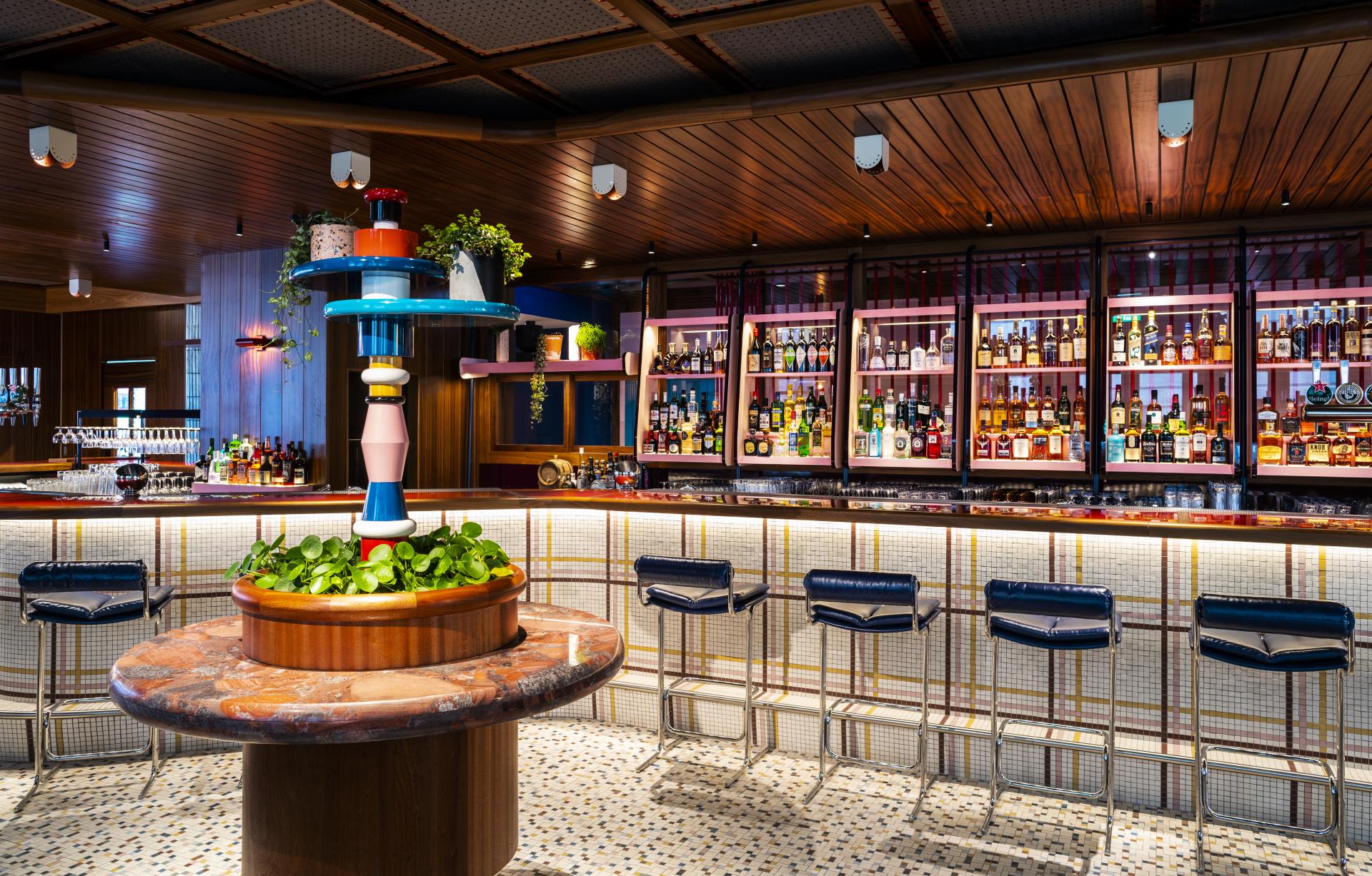 Stylish bar interior at The Standard, London, featuring colorful decor, unique centerpiece, and an extensive selection of spirits.