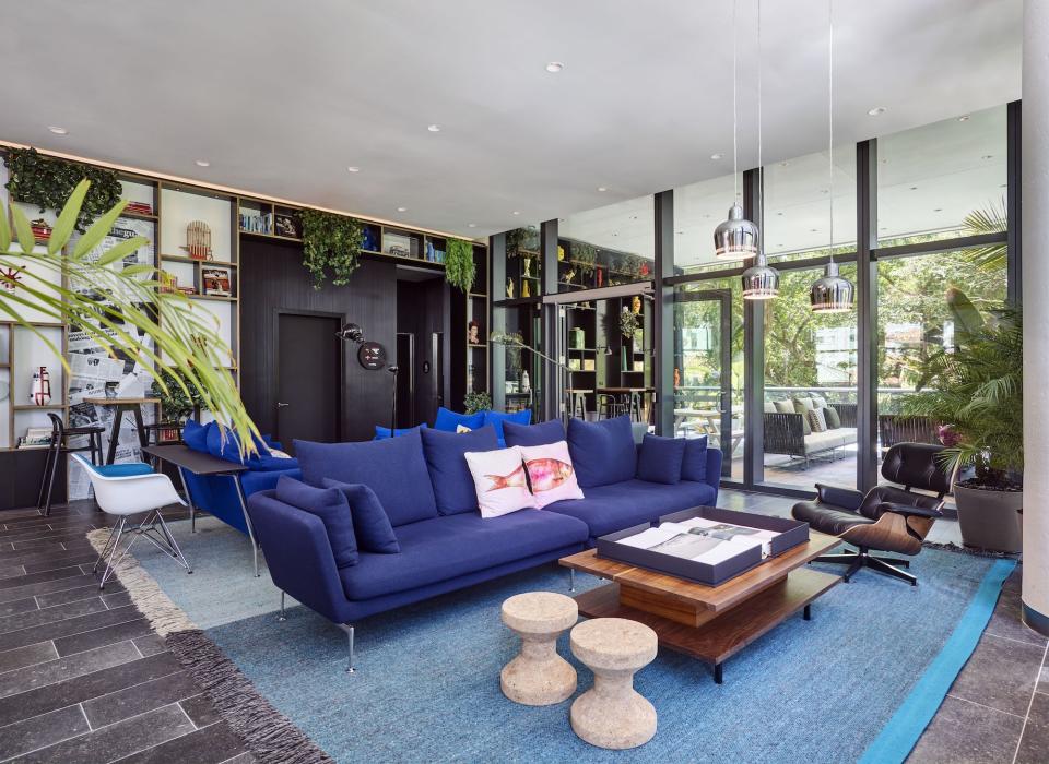 Modern hotel lobby featuring a stylish blue sofa, natural light, and contemporary decor at citizenM Miami.
