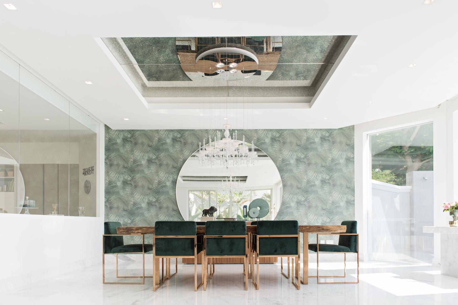 Minimalist dining area with green accents, elegant chandelier, and large mirror, designed for comfortable living in Dubai.