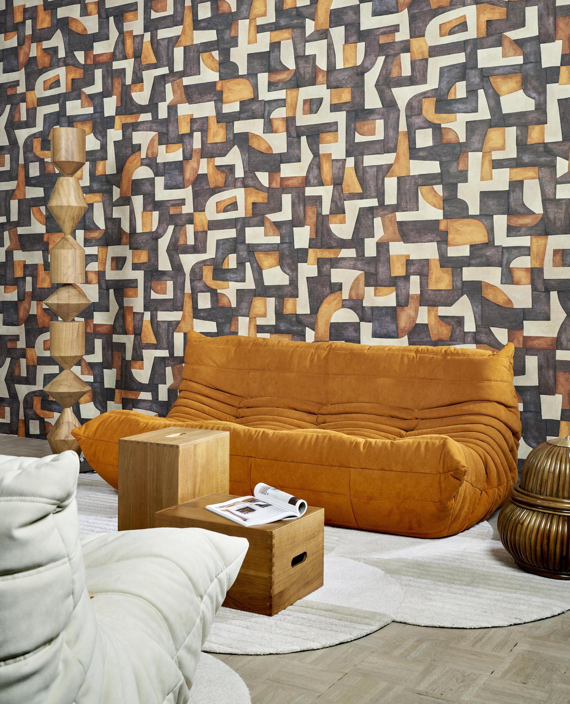 Modern abstract wallcovering featuring geometric shapes in earthy tones, complemented by contemporary furniture in a stylish interior setting.