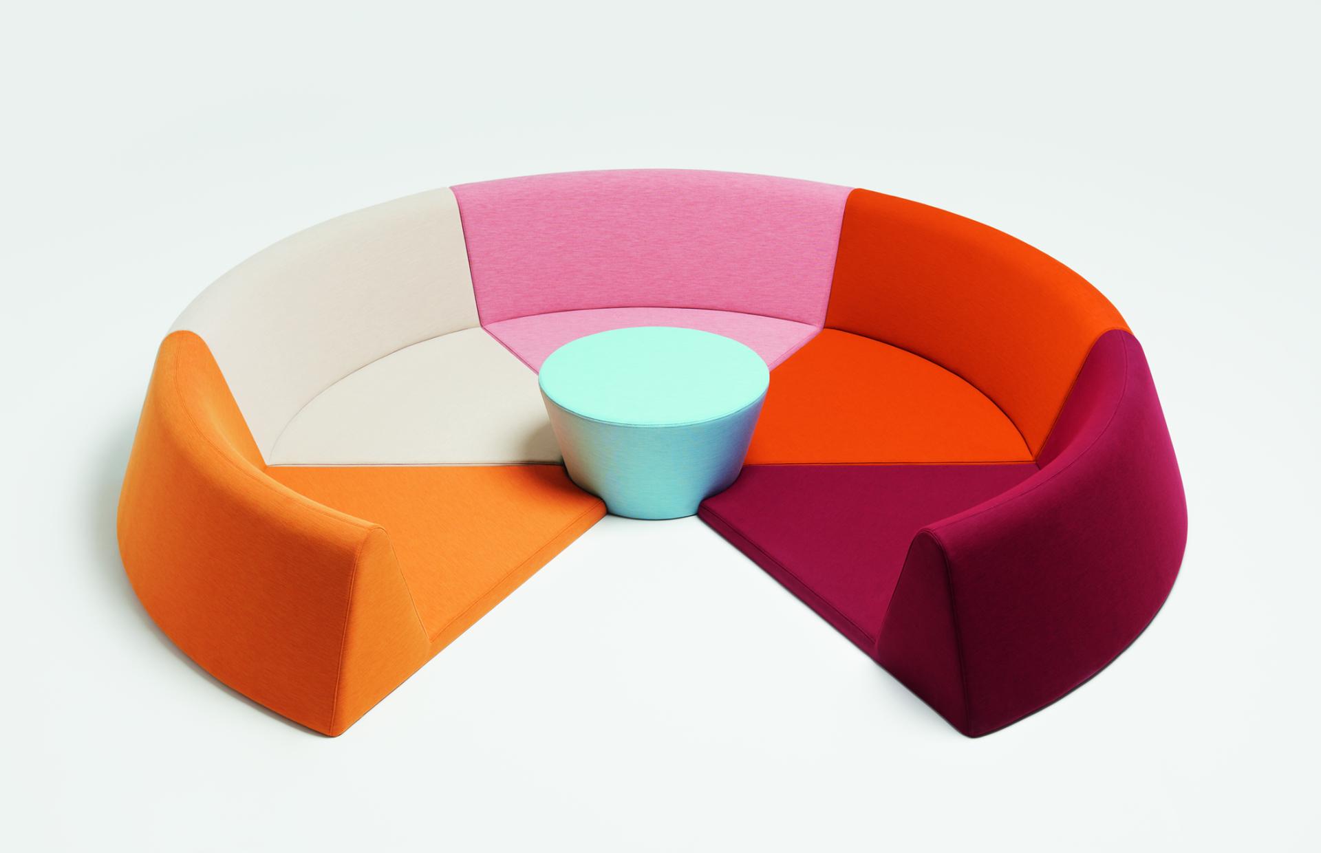 Vibrant, multi-colored knit fabric sofa with a round, mint-colored table, showcasing innovative design in knitted textiles.