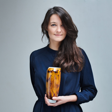 Designer Agnė Kučerenkaitė holds a unique handcrafted vase, symbolizing innovation and sustainable design from waste materials.