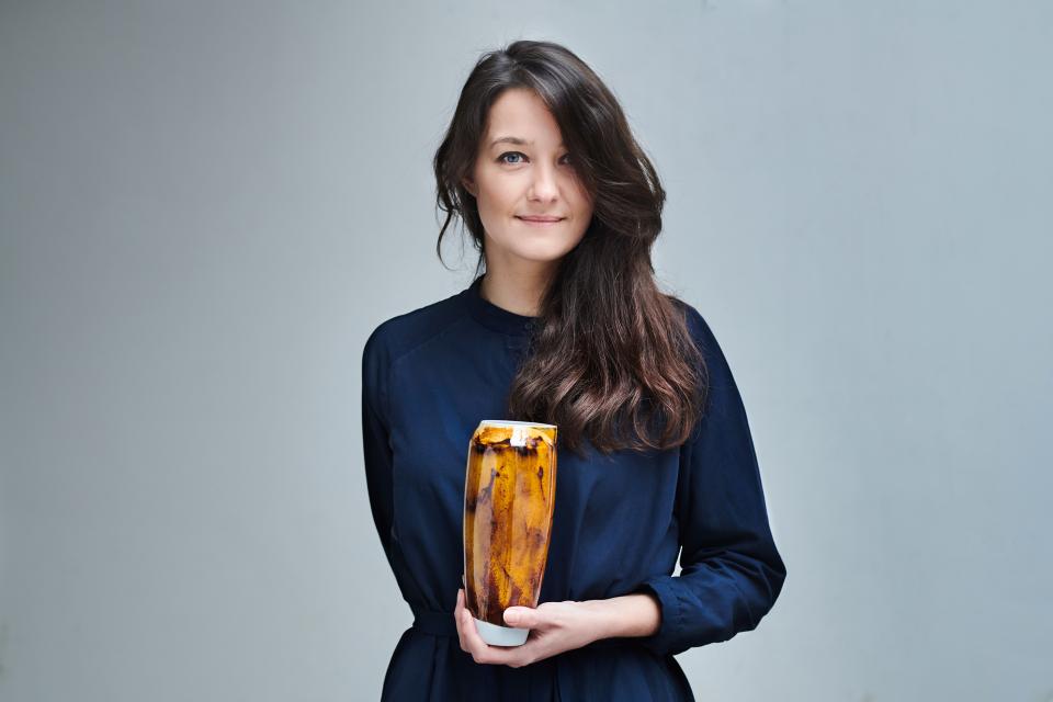 Designer Agnė Kučerenkaitė holds a unique handcrafted vase, symbolizing innovation and sustainable design from waste materials.
