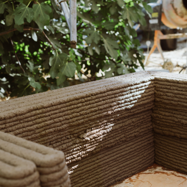 3D printing process for construction, showcasing a robotic arm applying concrete layers for sustainable building design.