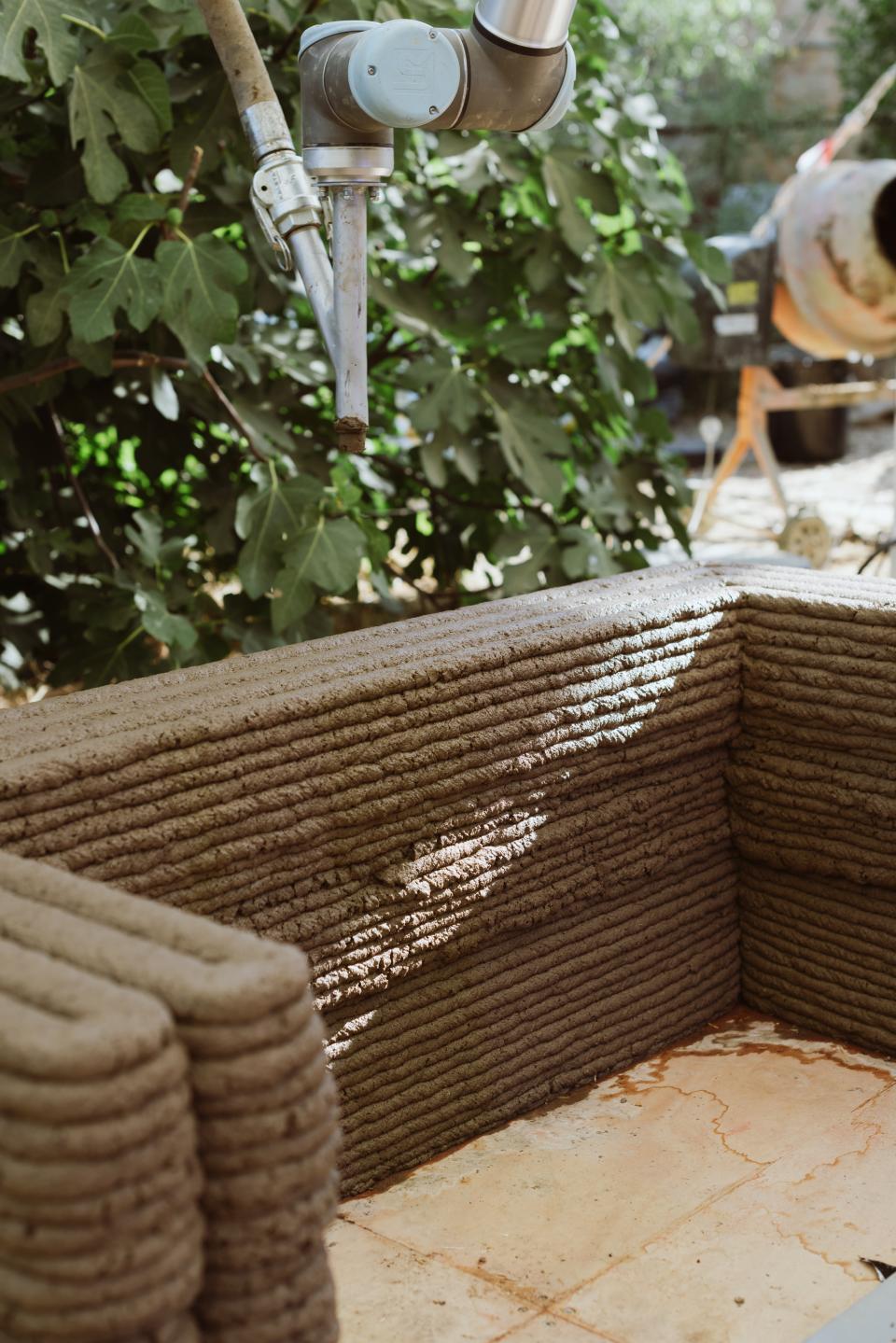 3D printing process for construction, showcasing a robotic arm applying concrete layers for sustainable building design.