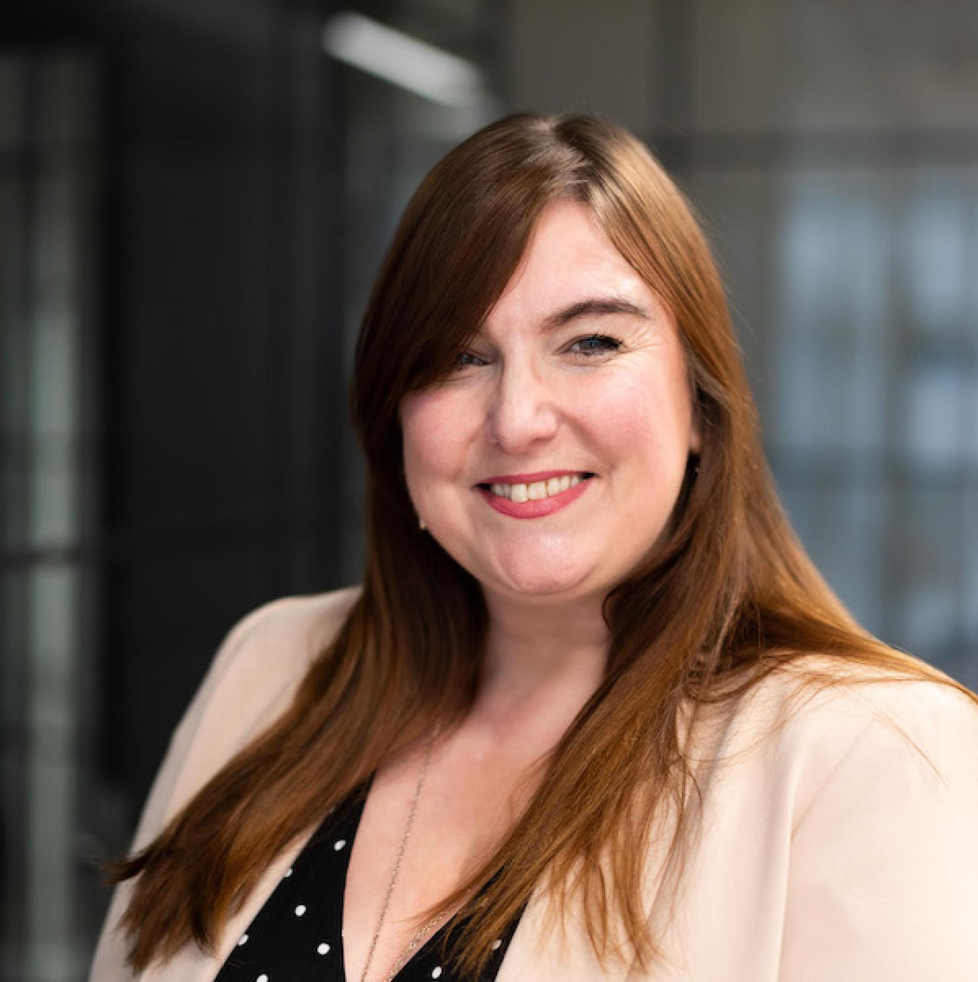 Professional woman smiling in a modern office environment, illustrating a forward-thinking workplace culture focused on collaboration and technology.