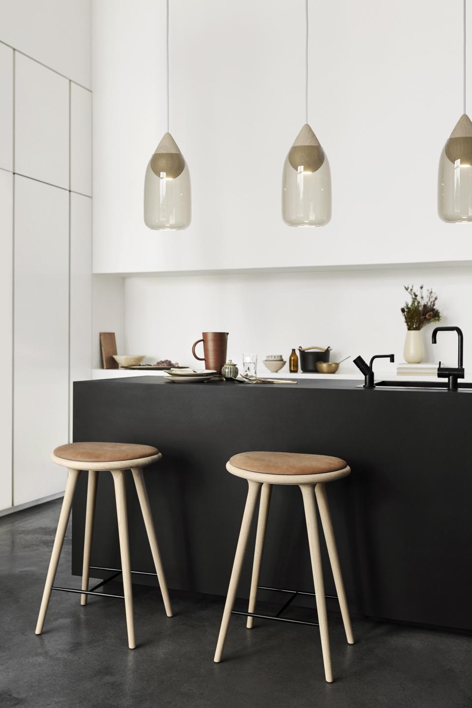 Contemporary kitchen featuring minimalist bar stools, elegant pendant lights, and stylish tableware by Mater for Salone del Mobile 2019.
