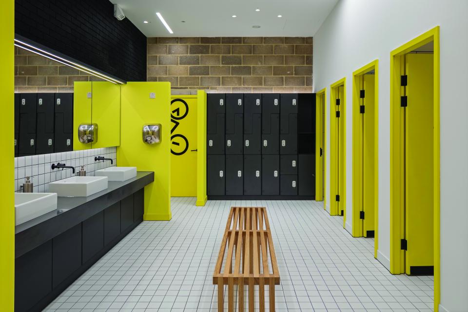 Brightly colored restroom interior featuring yellow lockers, sinks, and modern fixtures, designed for an office building retrofit.