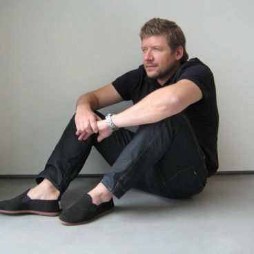 Designer David Fox seated contemplatively in a minimalist space, exploring emerging design trends and material aesthetics.