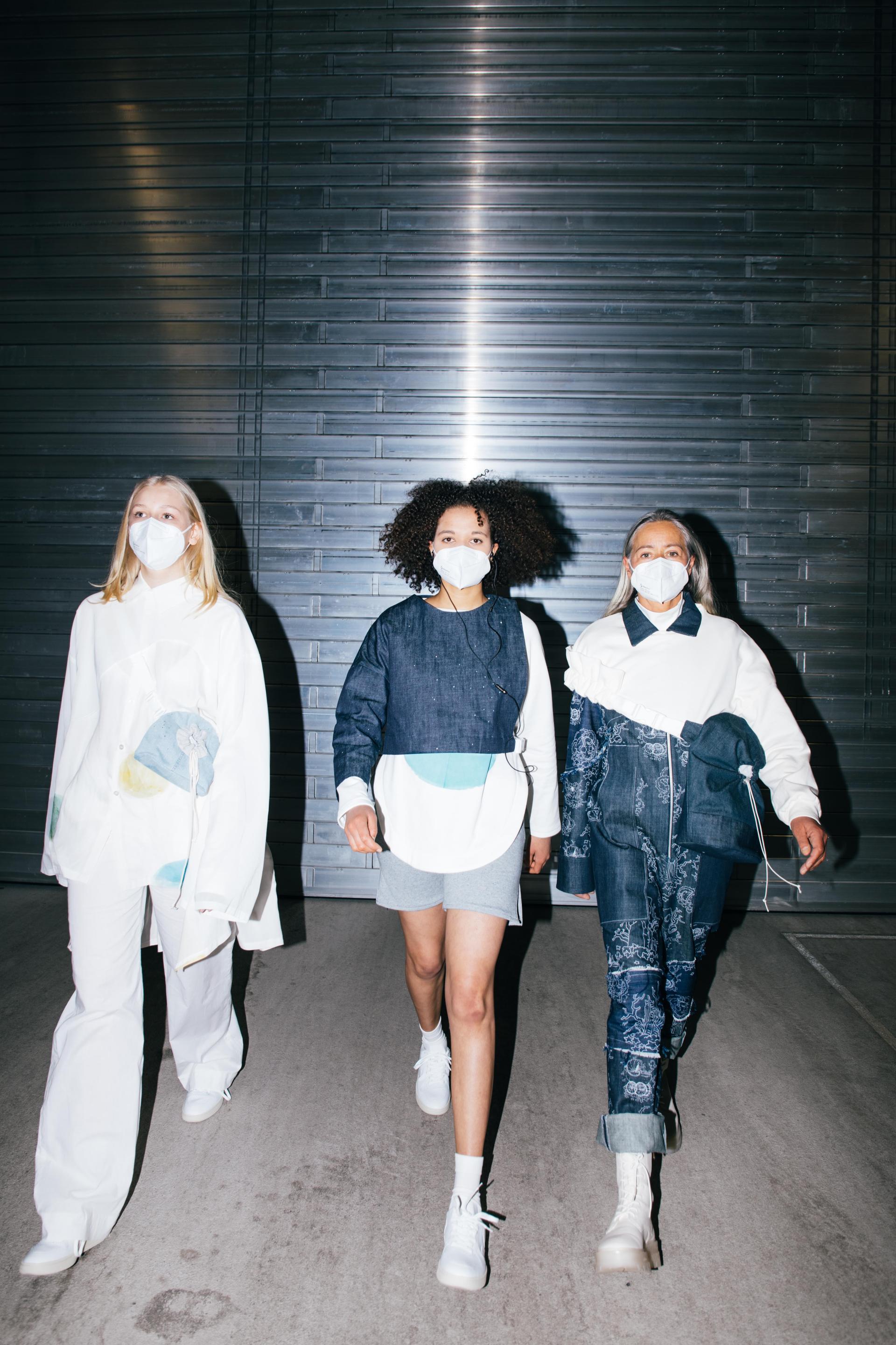 Three models showcase innovative, colorful fashion designs wearing masks, highlighting the trend of sustainability and creativity at DDW 2023.