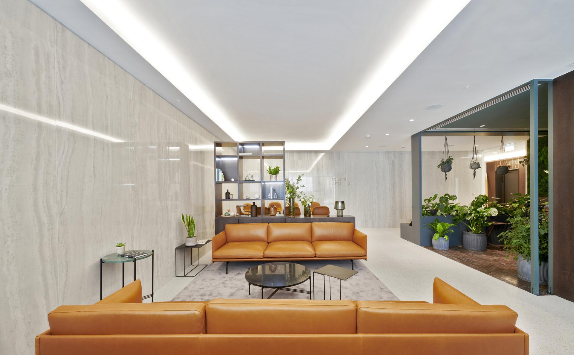 Elegant interior design by SpaceInvader featuring a leather sofa, modern shelving, and lush greenery at One Victoria Street, Windsor.