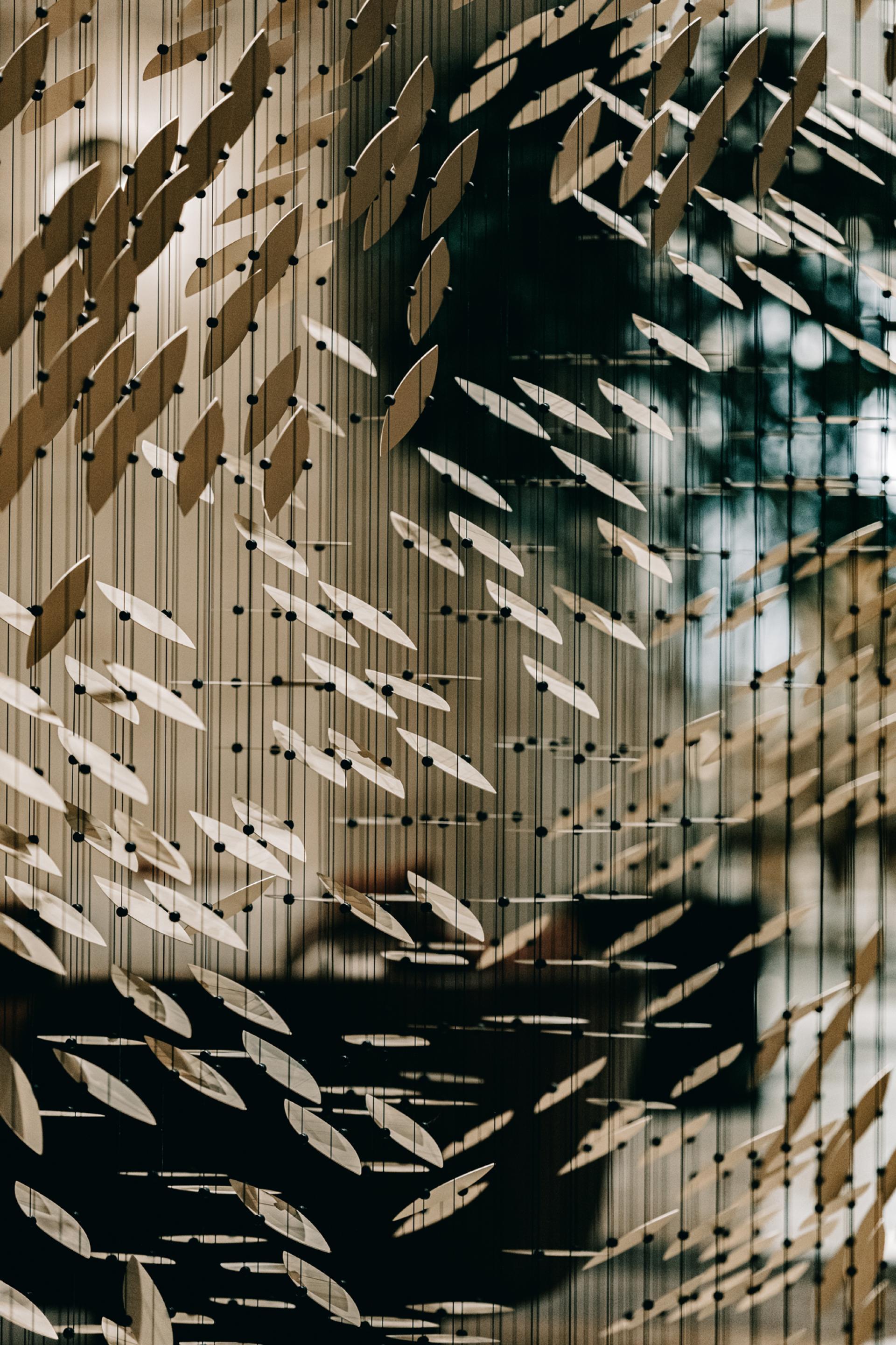 An intricate installation featuring layered, leaf-like forms suspended on strings, highlighting Giles Miller Studio's innovative design approach.