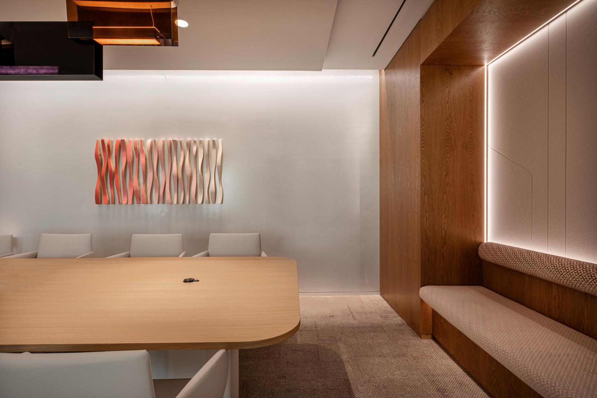 Modern office meeting space showcasing a wooden table, minimalist design, and vibrant wall art inspired by nature.
