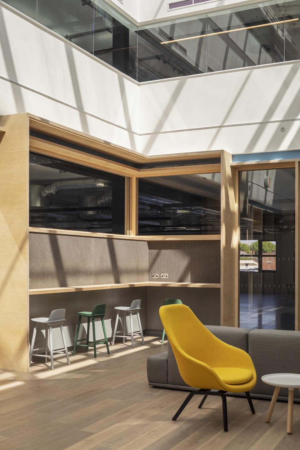 Bright and modern office interior featuring stylish yellow chair, wooden surfaces, and functional seating areas.