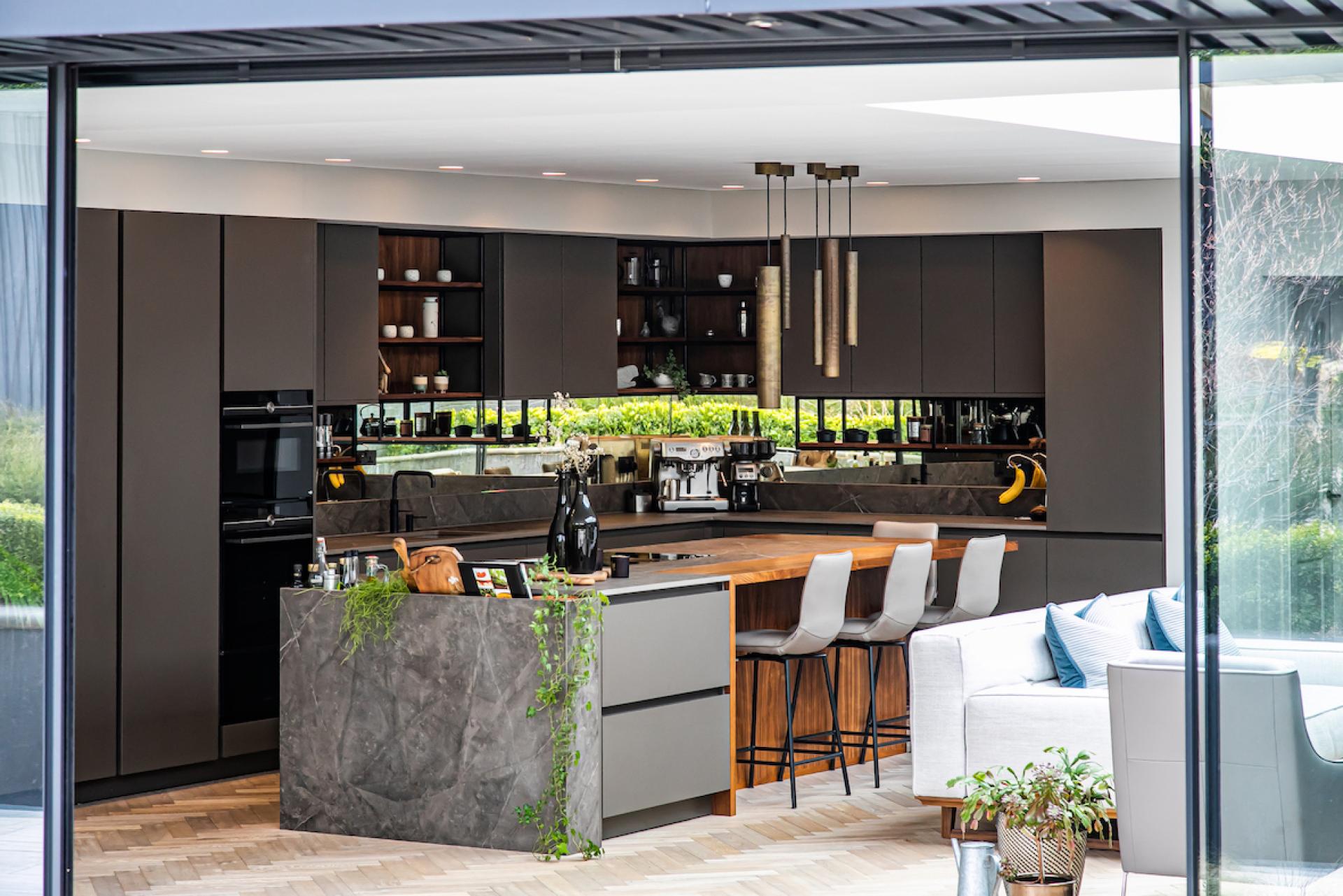 Stylish kitchen featuring contrasting Dekton surfaces, wooden accents, sleek cabinetry, and modern lighting for multifunctional living.