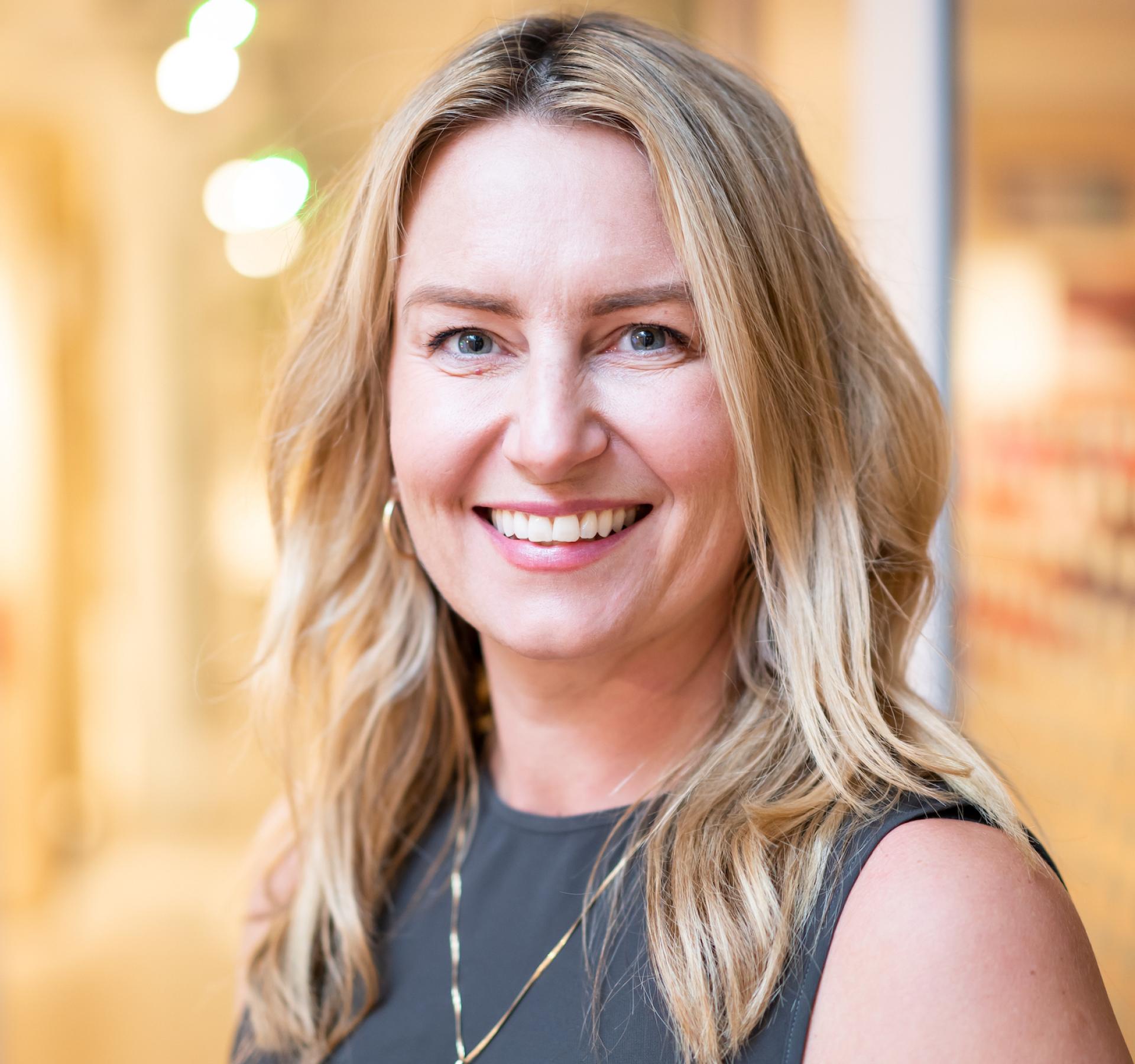 Smiling woman with long hair in a modern educational setting, illustrating the future of education and innovation.