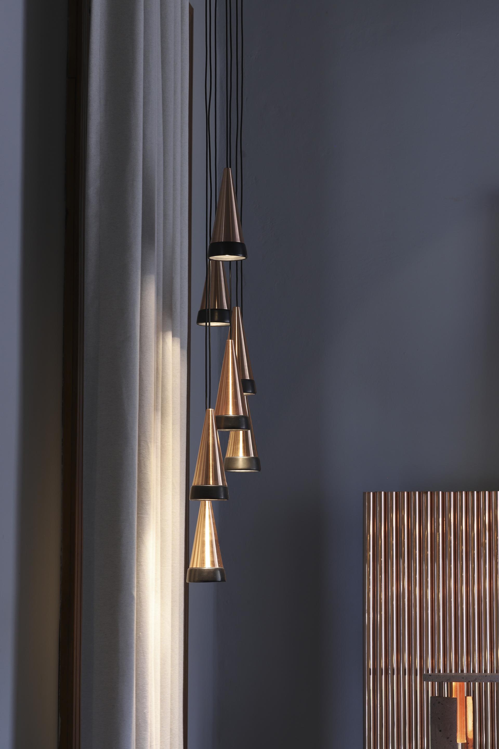 Hanging cone-shaped pendant lights illuminate a modern showroom, showcasing local materials in Davidpompa's Mexico City space.