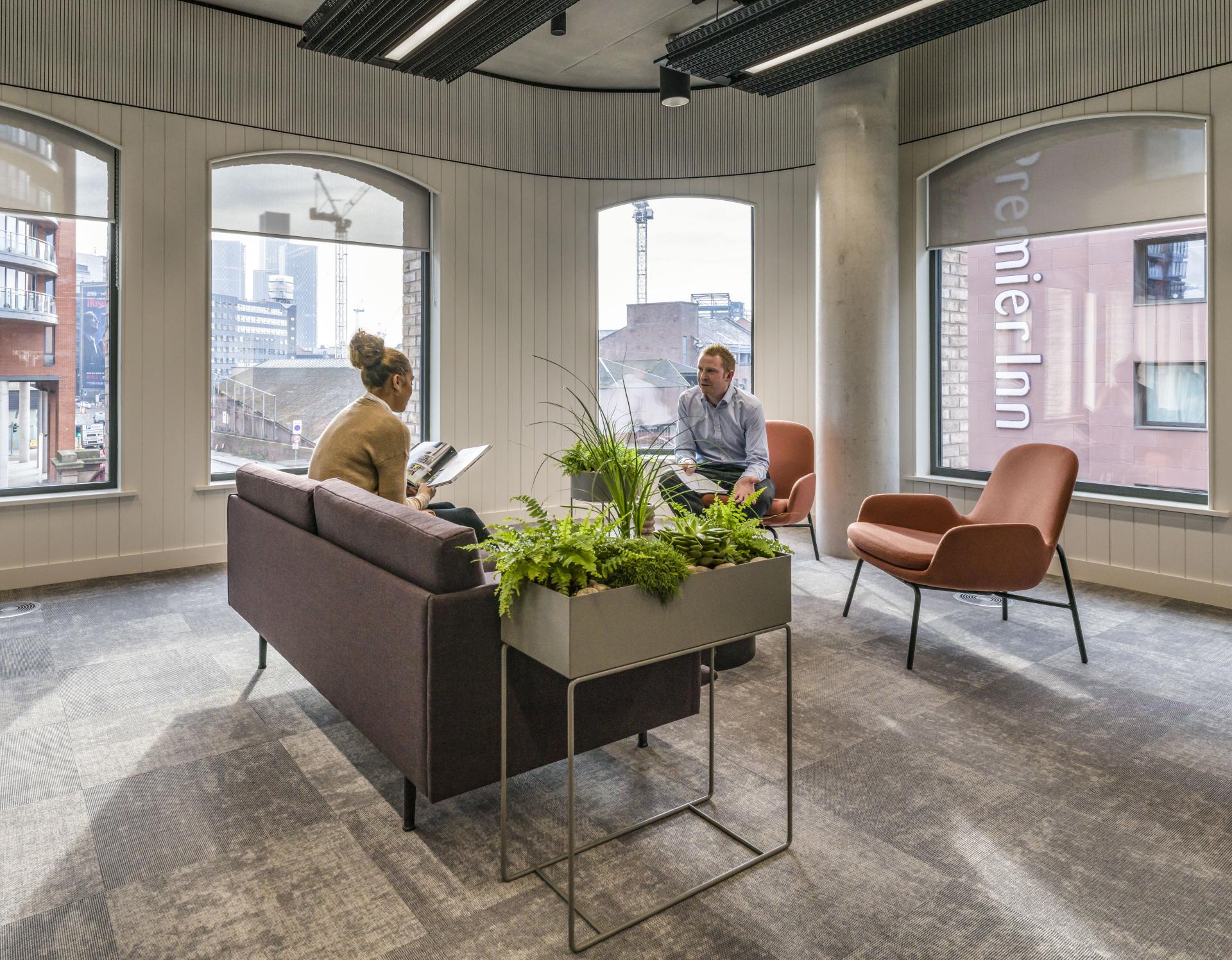 Modern office interior at Riverside House, showcasing a seating area with greenery, promoting workplace collaboration and design innovation.