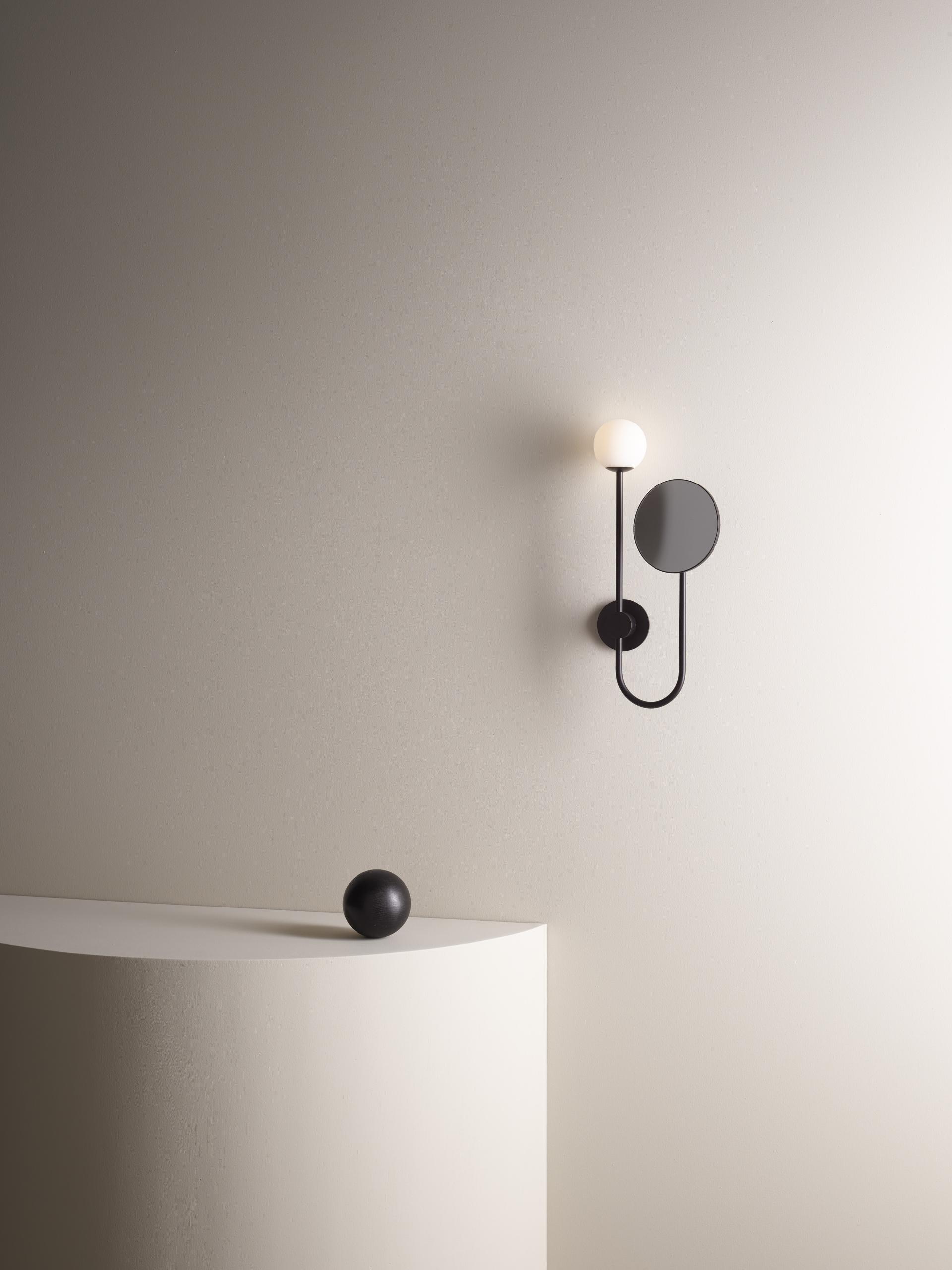 Sleek contemporary wall lamp and minimalistic black orb on a curved pedestal, showcasing Astro Lighting's design-led capsule collection.