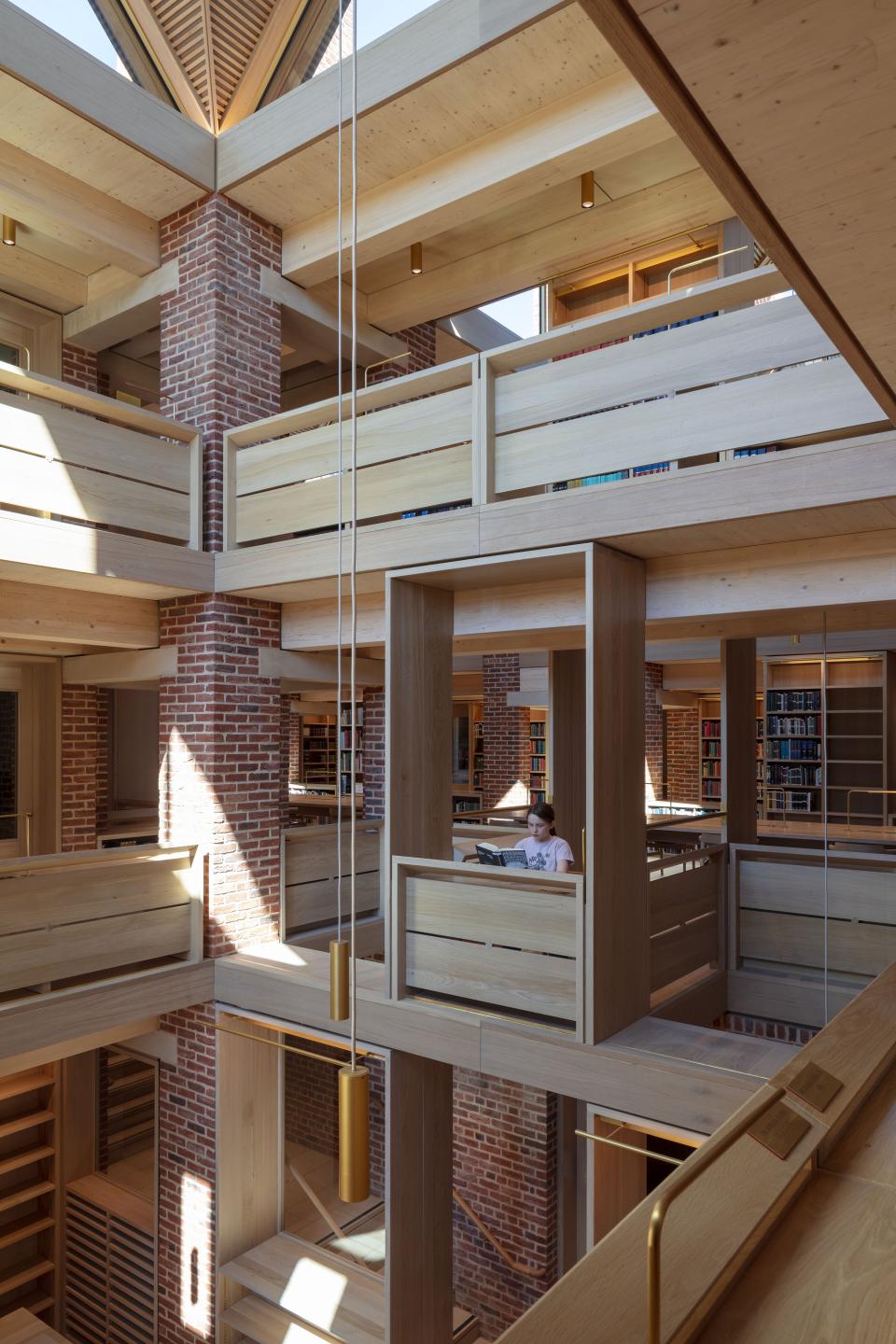 Modern library interior featuring wooden structures, bright natural light, and a girl reading in a cozy nook.