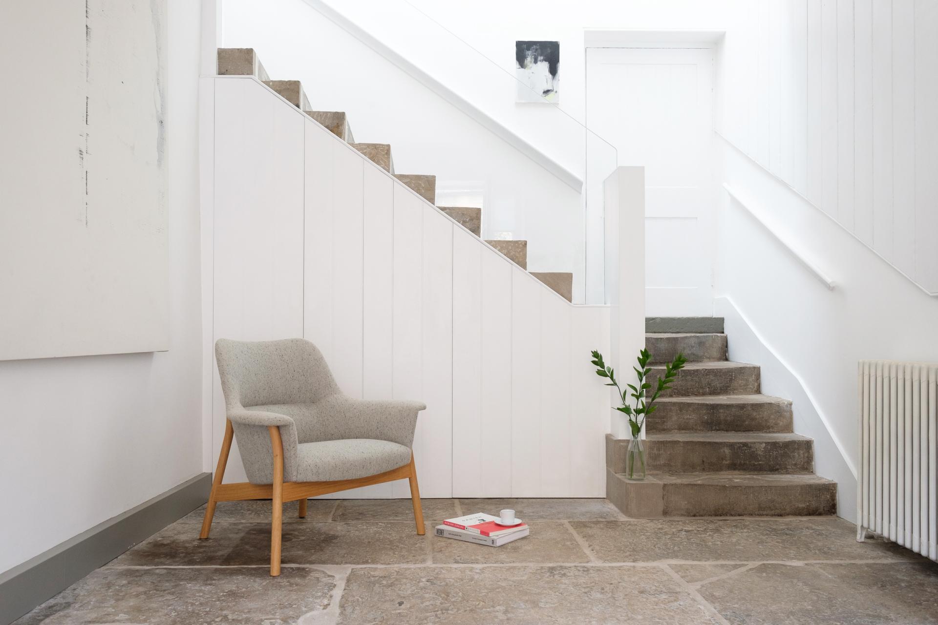 Modern British design featuring a stylish armchair, staircase, and minimal decor, showcasing Dare Studio's craftsmanship.