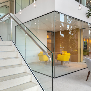 Modern showroom interior with glass walls, colorful seating, and a staircase, showcasing Studio Power's architectural design for Salboy.