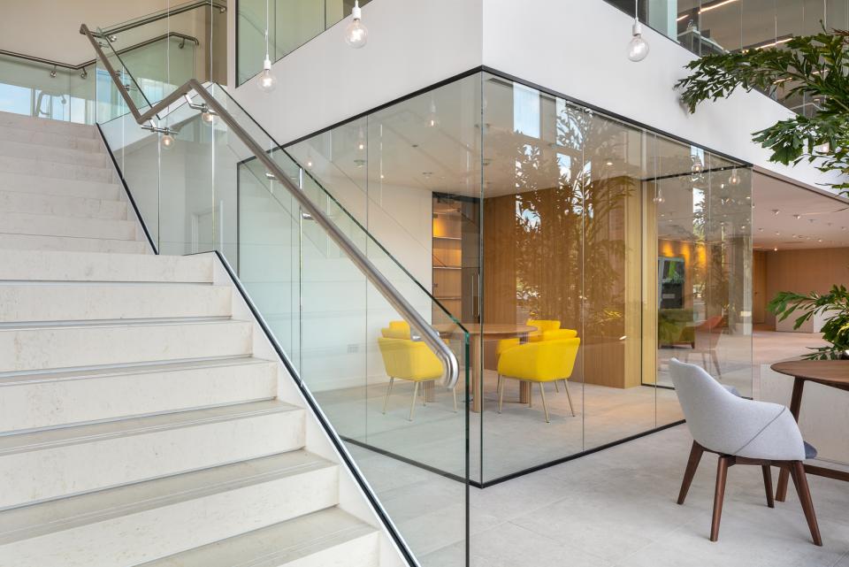 Modern showroom interior with glass walls, colorful seating, and a staircase, showcasing Studio Power's architectural design for Salboy.