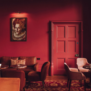 Luxurious interior of The Elvetham featuring rich red walls, elegant carpet, and stylish seating arrangements.