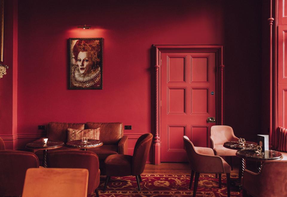 Luxurious interior of The Elvetham featuring rich red walls, elegant carpet, and stylish seating arrangements.