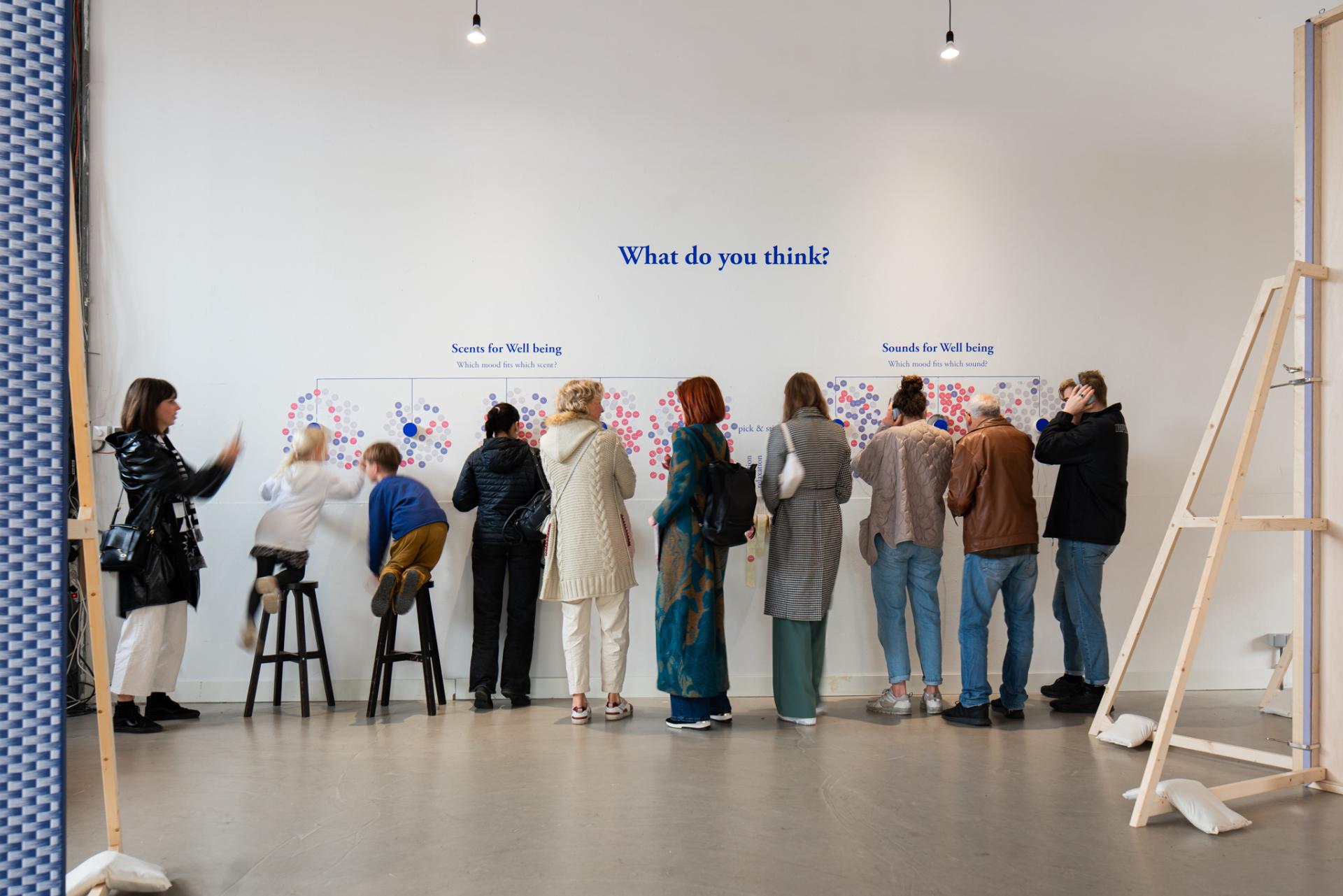 Participants engaging with interactive exhibits on scents and sounds for wellbeing in a contemporary design space.