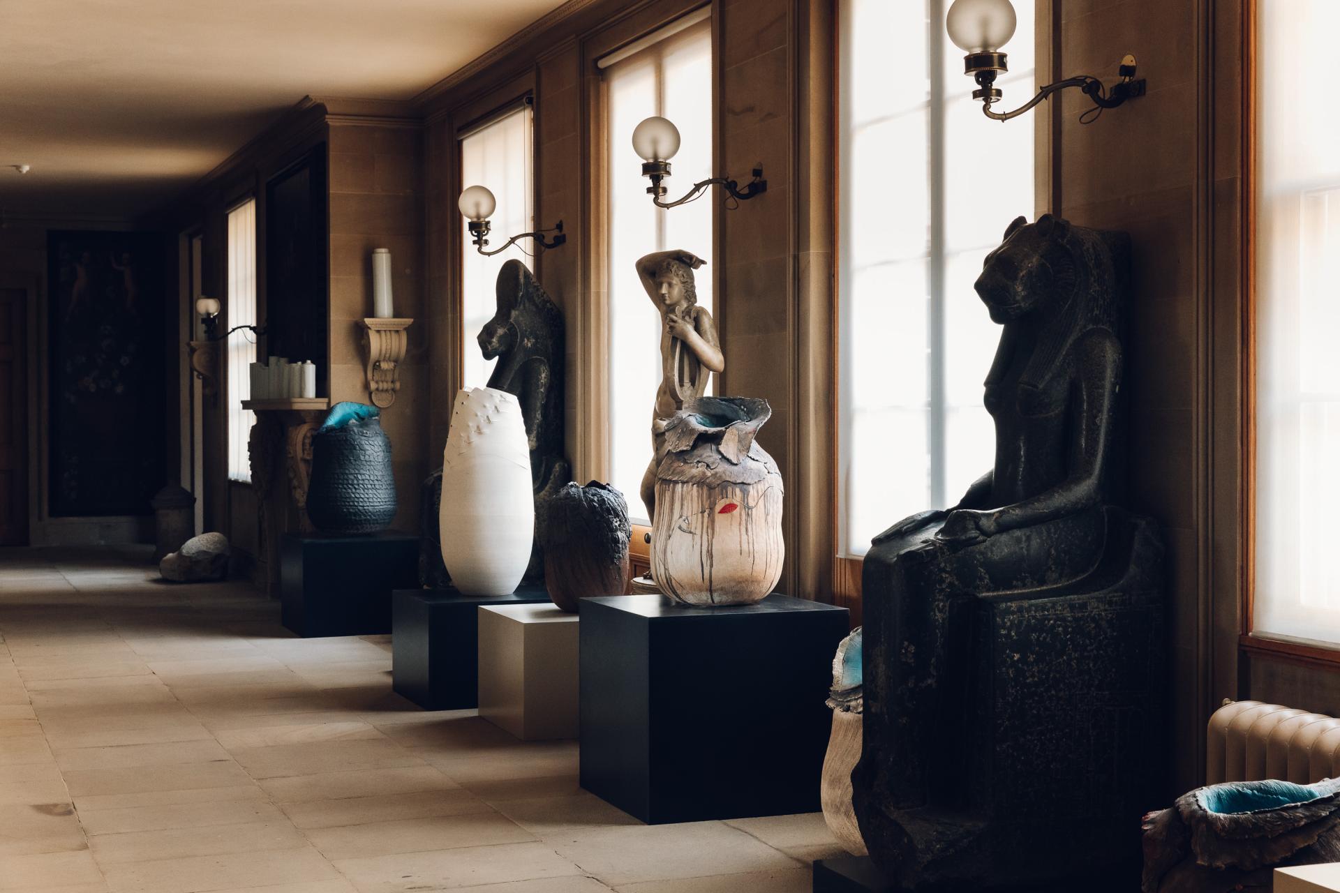 Contemporary and historical sculptures displayed in a well-lit corridor at Chatsworth House reflecting its artistic heritage.