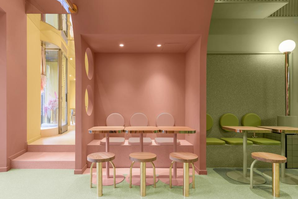 Colorful interior design of Masquespacio’s Bun restaurant, featuring pink and green seating with stylish wood and metal tables.