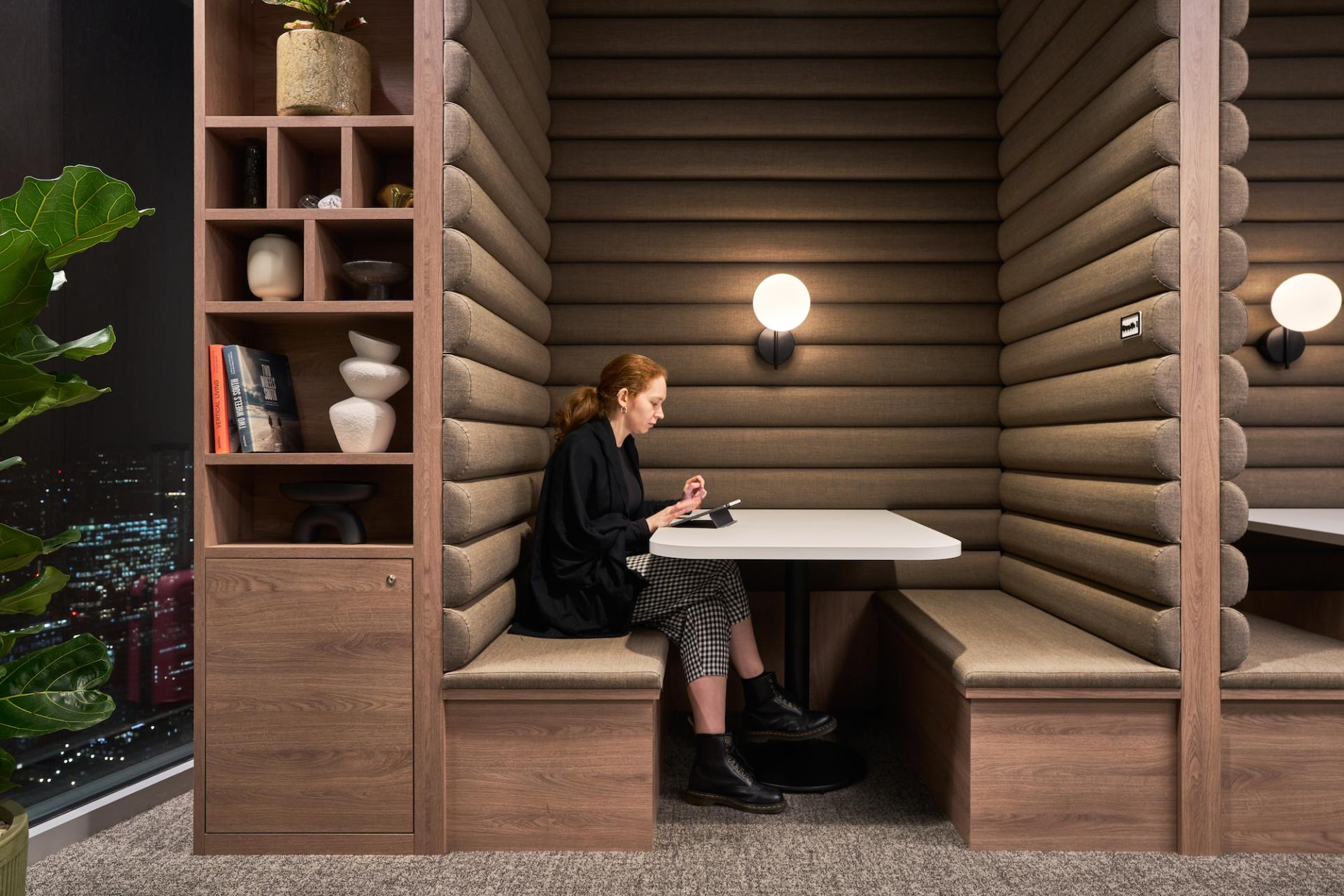 Modern workplace design featuring a woman using a tablet in a cozy booth at Bentley Systems' office.