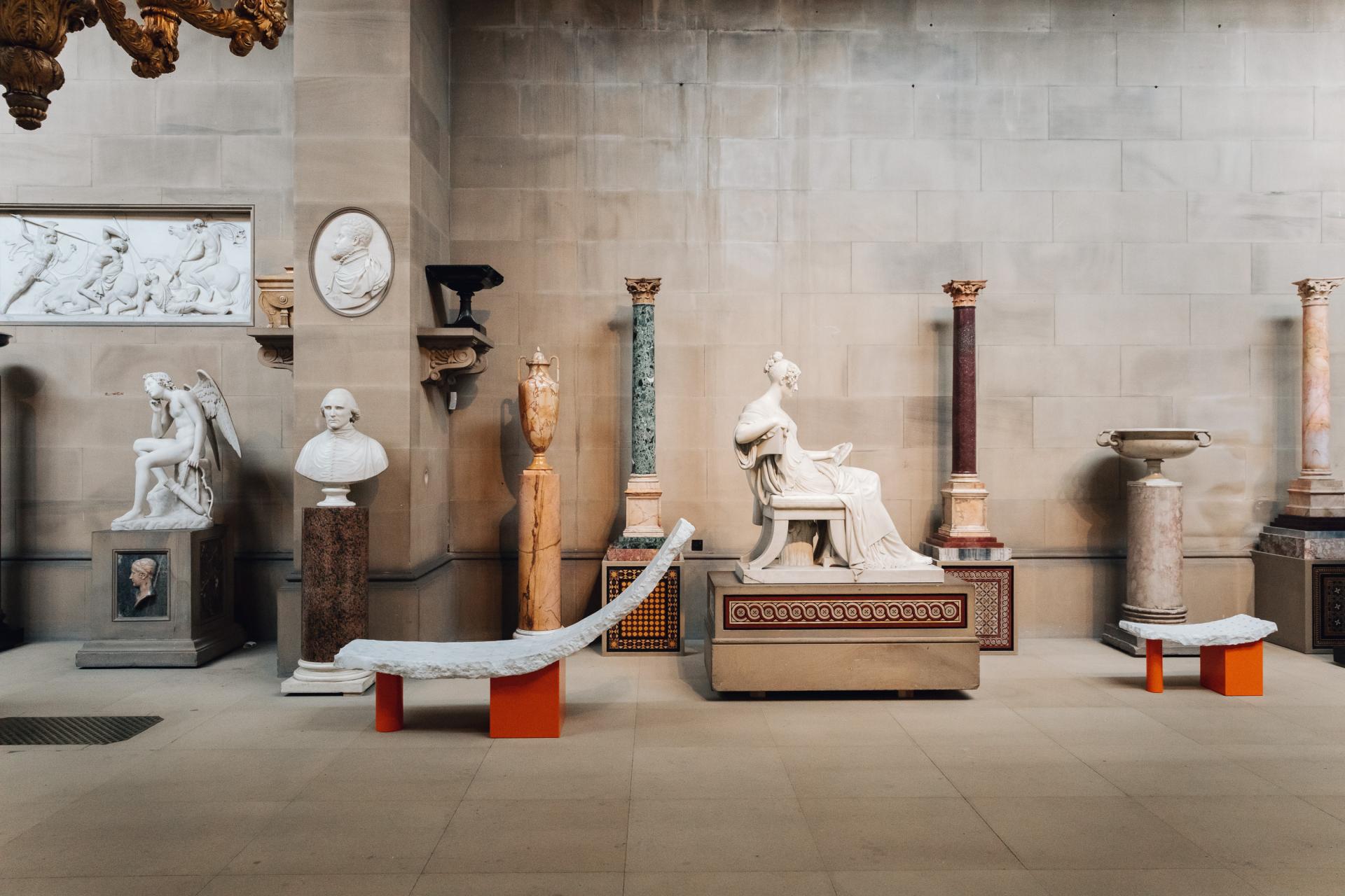 A gallery in Chatsworth House showcasing classical sculptures, marble busts, and ornate columns reflecting its artistic heritage.