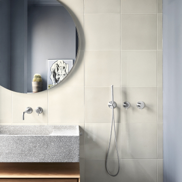 Stylish bathroom design by Emil Thorup featuring d line's Qtoo collection, a round mirror, and textured surfaces.