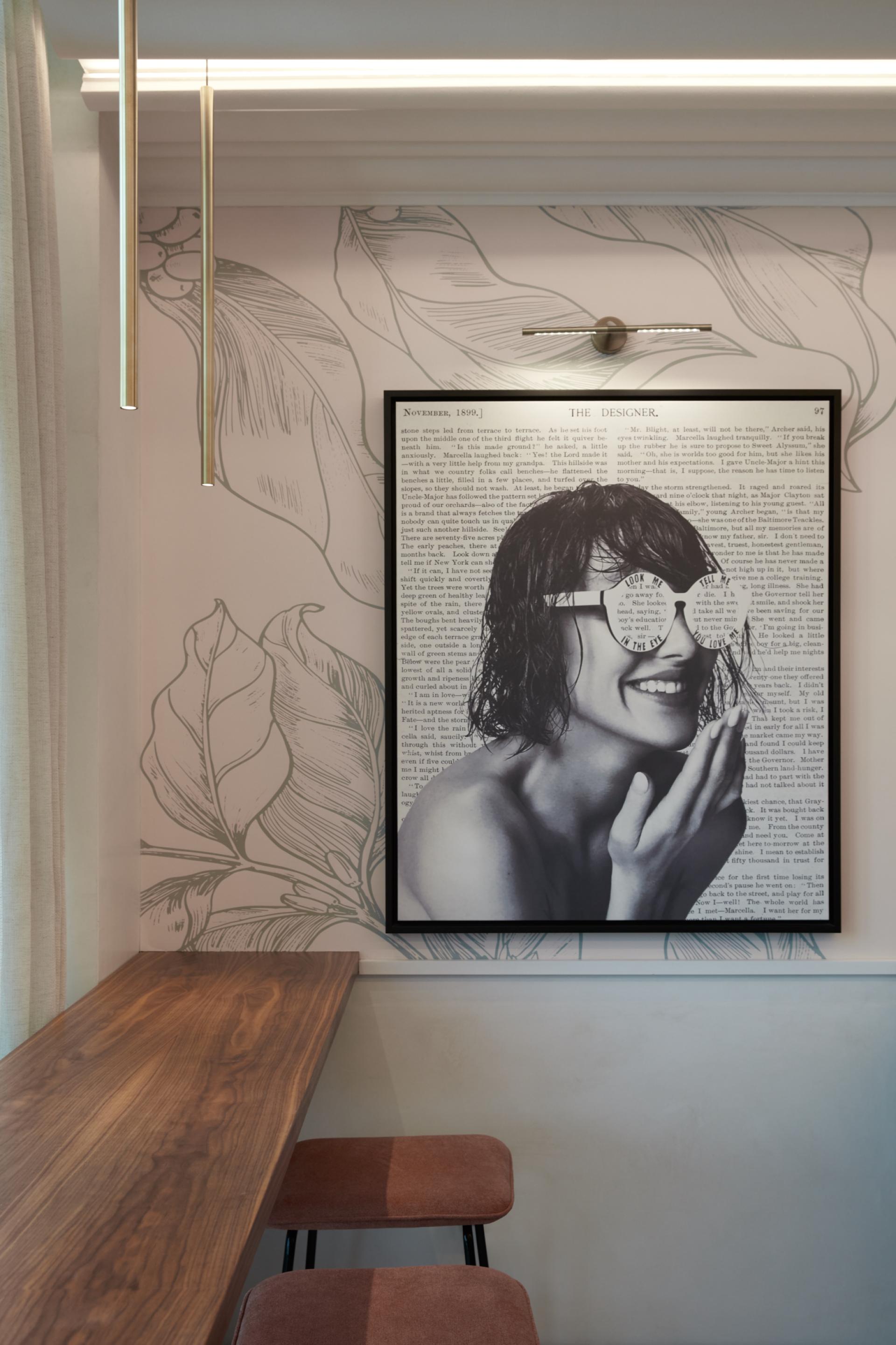 Contemporary art piece featuring a smiling woman with artistic sunglasses, set against a botanical wallpaper backdrop in The8 Hotel, Dubai.