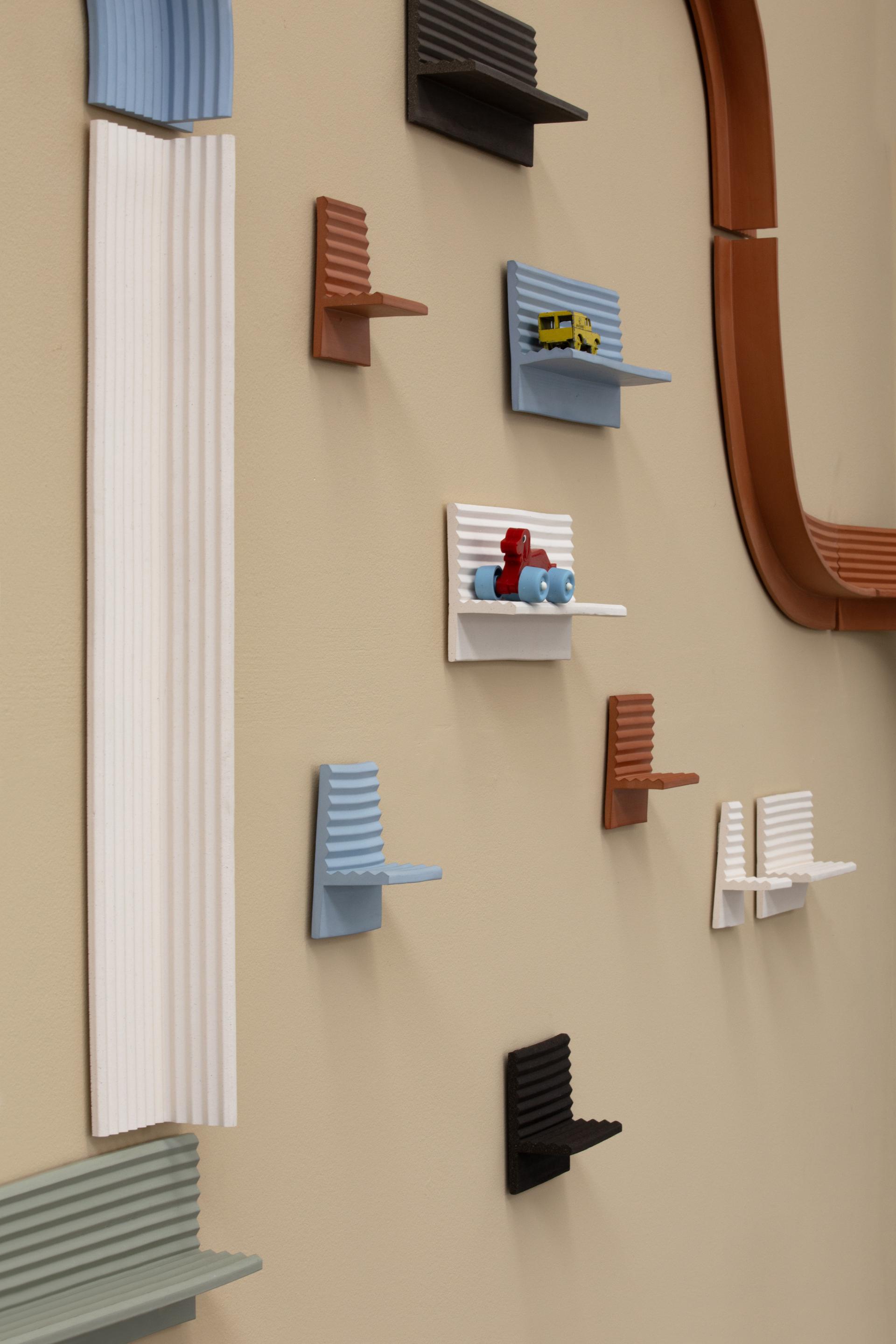 Colorful, textured wall shelves displayed creatively, showcasing Ewan Crallan's playful yet purposeful design style in interior decor.