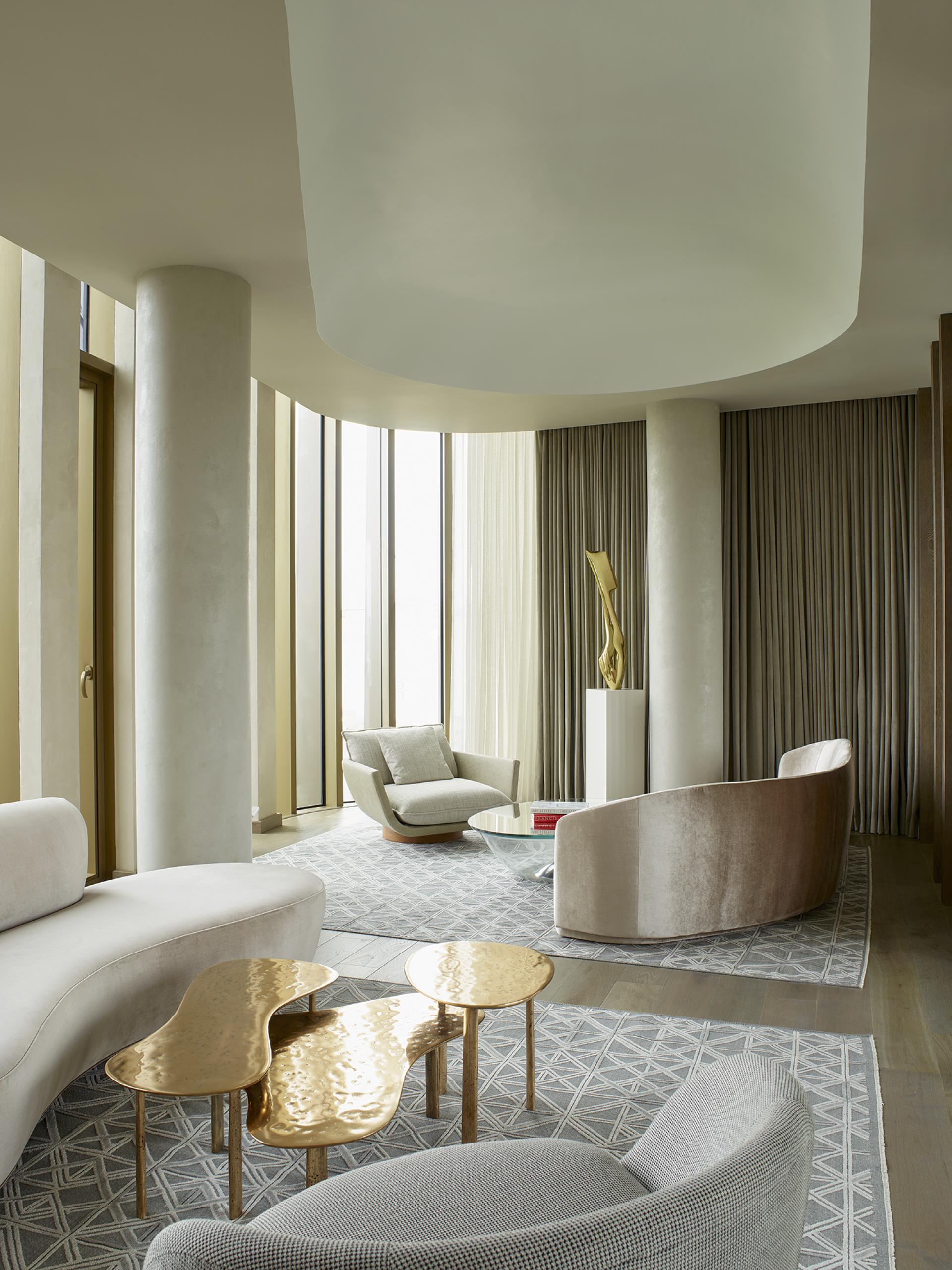 Luxurious, modern hotel lounge in Leicester Square featuring sculptural furniture, golden tables, and large windows.