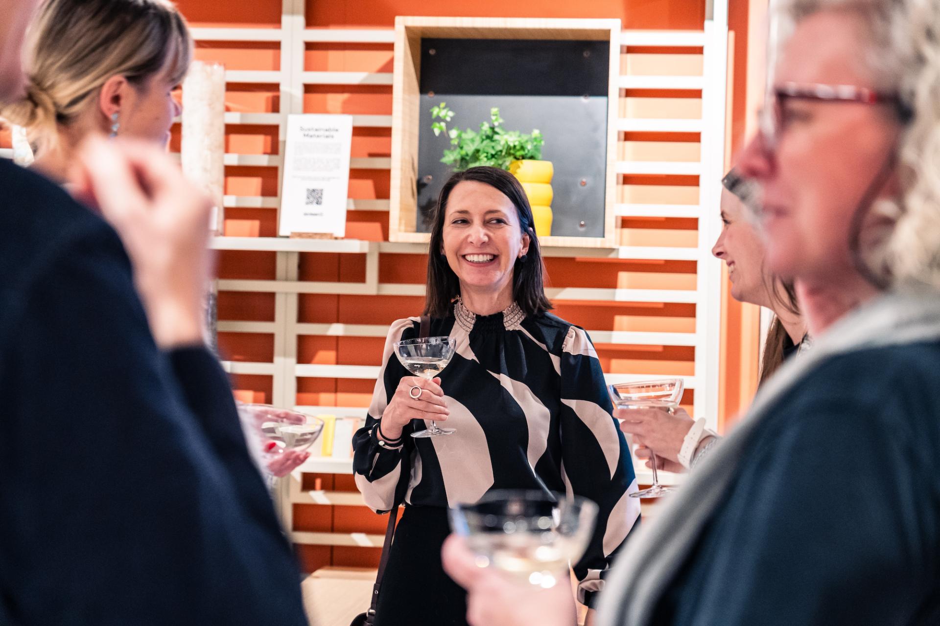 Anna Campbell-Jones smiles while holding a glass at a gathering in Material Source Studio, Glasgow.